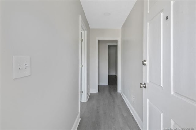 corridor with baseboards and wood finished floors
