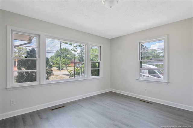 spare room with wood finished floors, baseboards, and a textured ceiling