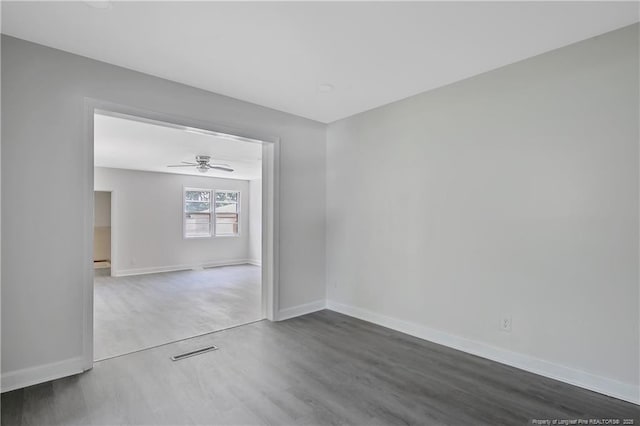 empty room featuring dark wood-style floors, baseboards, and ceiling fan