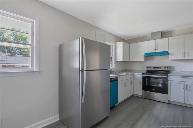 kitchen featuring stainless steel appliances, a sink, under cabinet range hood, light countertops, and white cabinets
