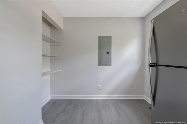 unfurnished room with electric panel, wood finished floors, and baseboards