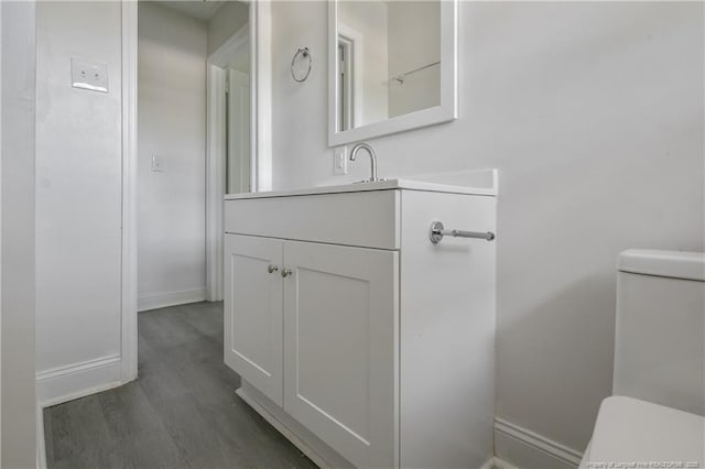 bathroom featuring toilet, wood finished floors, vanity, and baseboards