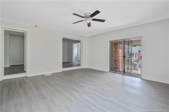empty room featuring a ceiling fan, baseboards, and wood finished floors