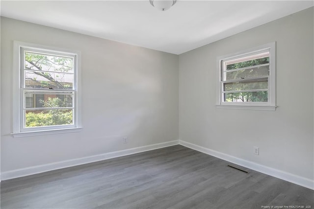 unfurnished room featuring plenty of natural light, dark wood-style flooring, and baseboards