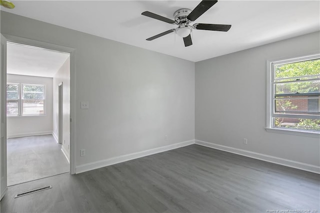 unfurnished room featuring healthy amount of natural light, dark wood-style flooring, and a ceiling fan