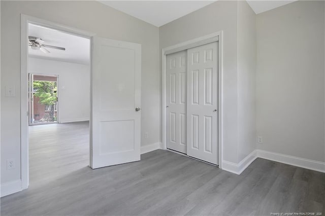 unfurnished bedroom featuring wood finished floors, baseboards, and a closet