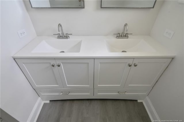full bath featuring wood finished floors, double vanity, and baseboards