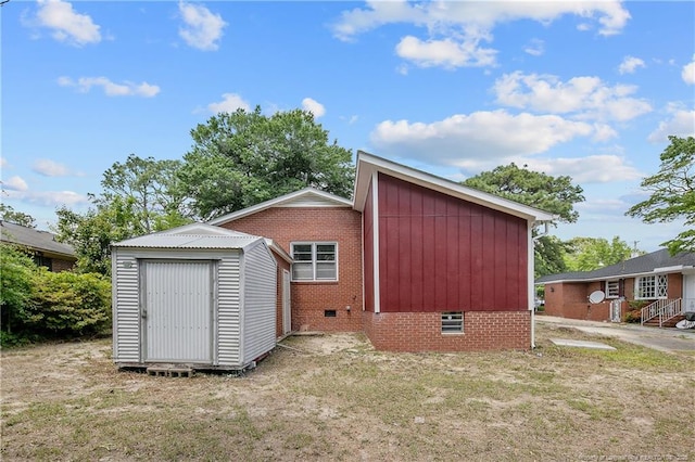 rear view of property featuring crawl space, a storage shed, an outbuilding, and a yard