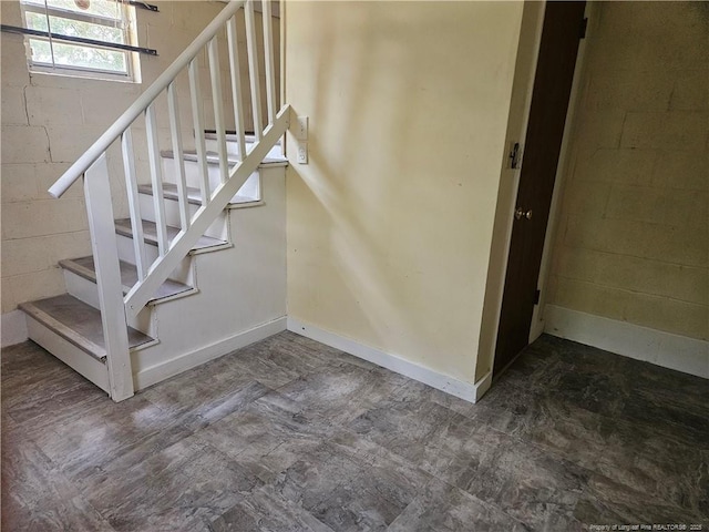 stairway featuring concrete block wall and baseboards