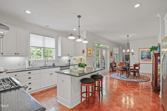 kitchen with a sink, recessed lighting, a chandelier, white cabinetry, and backsplash