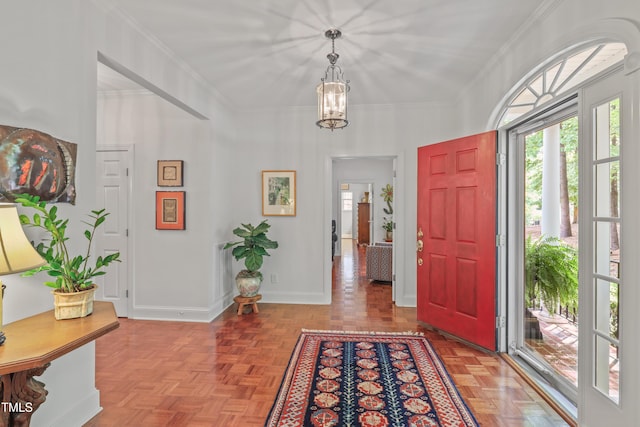 foyer entrance featuring a chandelier, crown molding, and baseboards
