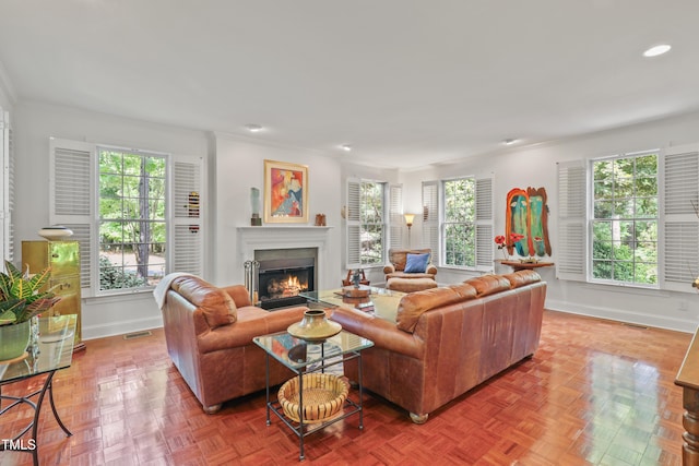 living area with baseboards, plenty of natural light, crown molding, and recessed lighting
