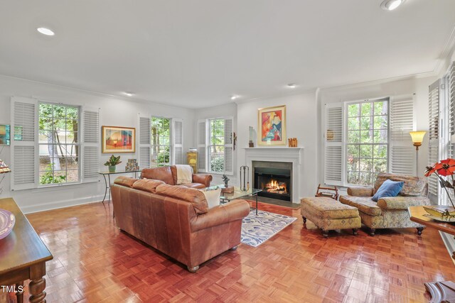 living room with ornamental molding, plenty of natural light, a fireplace with flush hearth, recessed lighting, and baseboards