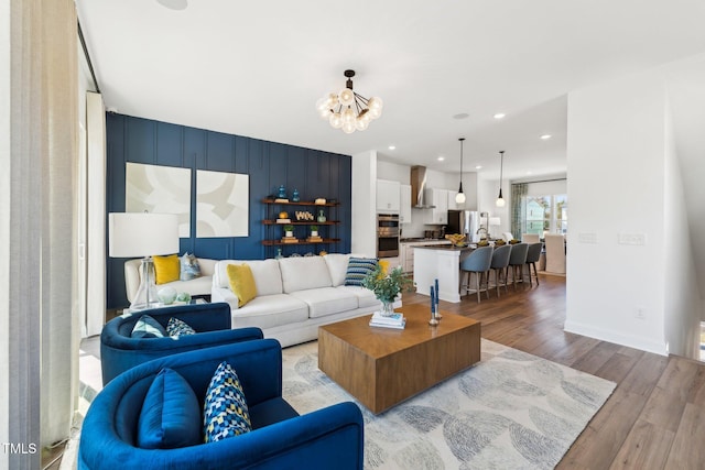 living room featuring light wood finished floors, a chandelier, recessed lighting, and baseboards