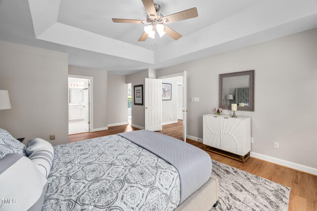 111 Gingergate Dr, Cary, NC 27519 - bedroom with a tray ceiling, wood finished floors, ensuite bath, and ceiling fan