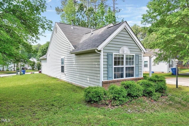 view of side of property with a lawn, roof with shingles, and brick siding