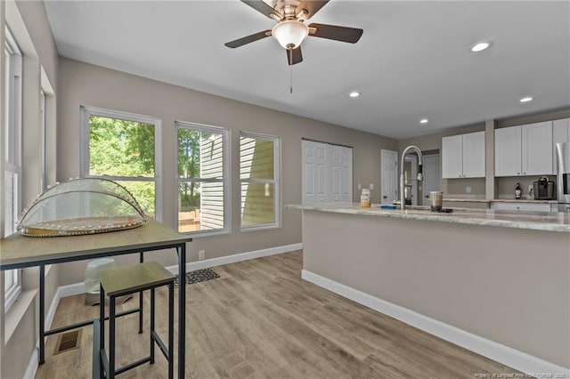 300 Fox Ridge Rd, Warsaw, NC 28398 - kitchen with a ceiling fan, baseboards, white cabinetry, light stone counters, and light wood-type flooring