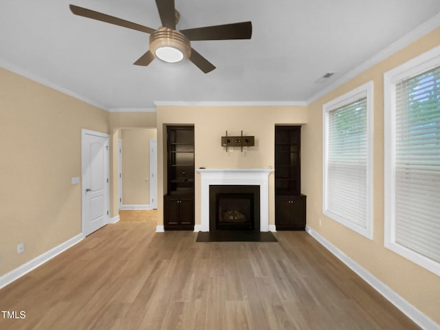 unfurnished living room featuring ceiling fan, wood finished floors, baseboards, a fireplace with flush hearth, and crown molding