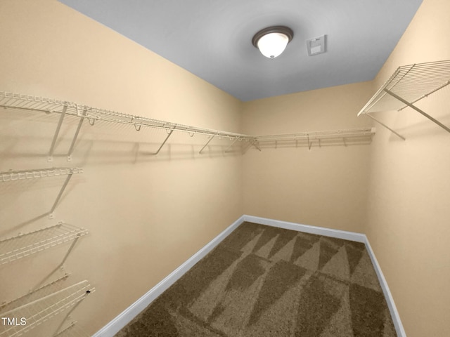 spacious closet featuring dark colored carpet