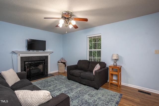 129 Clark Ct, Youngsville, NC 27596 - living area with ceiling fan, wood finished floors, baseboards, a fireplace with raised hearth, and a textured ceiling