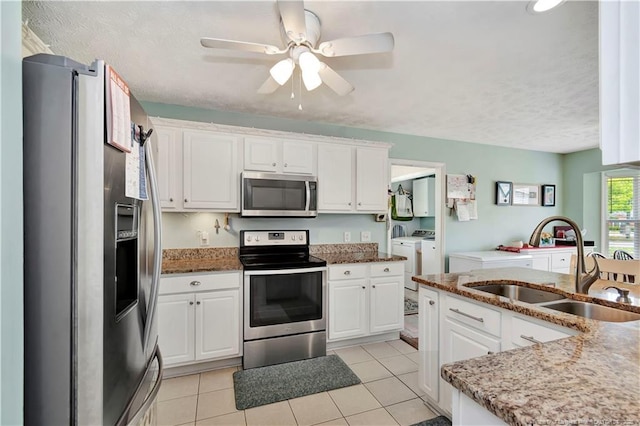 1501 E 6th St, Lumberton, NC 28358 - kitchen with appliances with stainless steel finishes, washer and dryer, a sink, white cabinets, and a textured ceiling