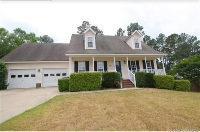 cape cod house with driveway, an attached garage, a porch, and a front yard