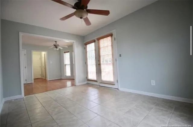 empty room featuring ceiling fan, light tile patterned floors, and baseboards