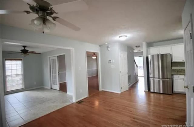 kitchen featuring freestanding refrigerator, a ceiling fan, white cabinets, and wood finished floors