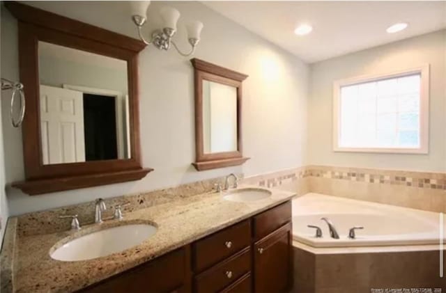 bathroom featuring a bath, double vanity, and recessed lighting