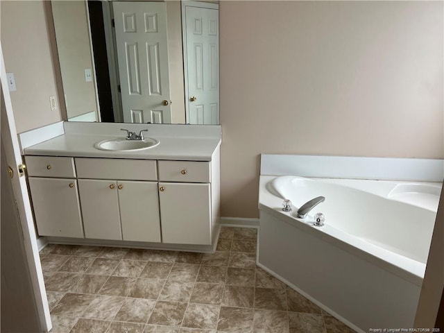 bathroom with vanity, a garden tub, and baseboards
