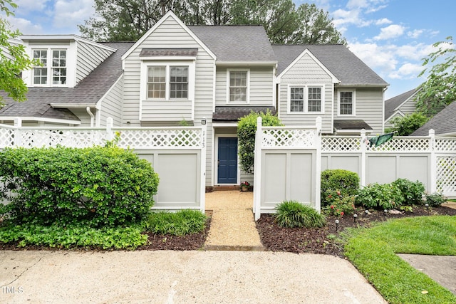 view of front facade with roof with shingles and fence