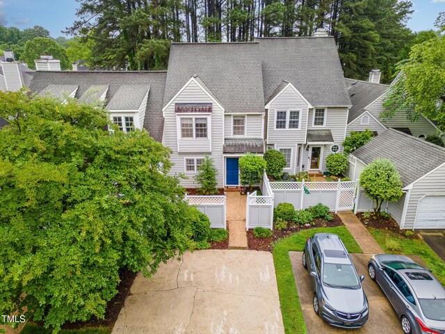 back of property with fence, a shingled roof, and uncovered parking
