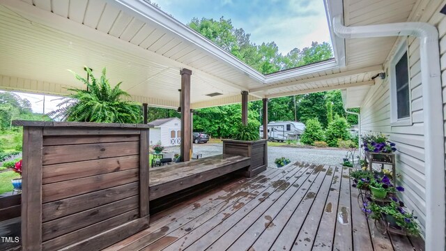 wooden terrace with a storage shed and an outdoor structure