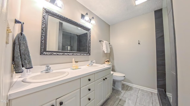 bathroom with double vanity, toilet, baseboards, and a textured ceiling