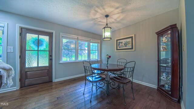 dining space featuring dark wood-type flooring, baseboards, and a textured ceiling