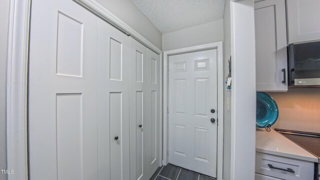 doorway with a textured ceiling and dark tile patterned floors