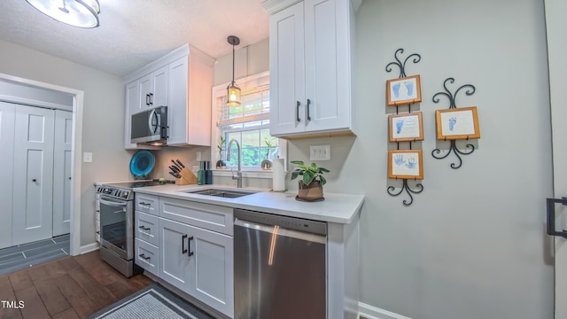 kitchen with appliances with stainless steel finishes, a sink, dark wood-style floors, baseboards, and light countertops