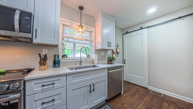 kitchen featuring stainless steel appliances, a sink, dark wood-style floors, light countertops, and white cabinets