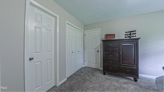 bedroom featuring dark carpet, baseboards, and a textured ceiling