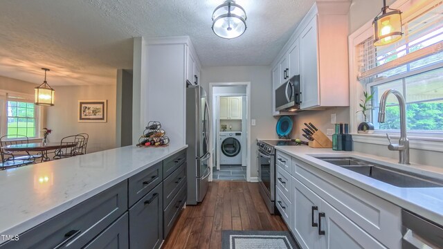 kitchen featuring washer / dryer, stainless steel appliances, a sink, a textured ceiling, and light countertops
