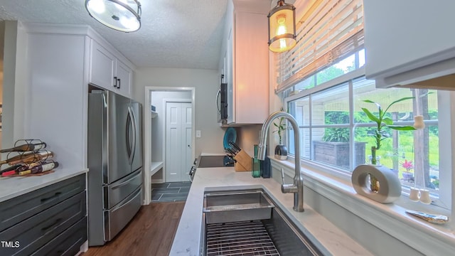 kitchen featuring appliances with stainless steel finishes, white cabinets, a textured ceiling, dark wood-style floors, and light stone counters
