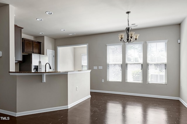 kitchen featuring stainless steel fridge, dark brown cabinets, dark wood-style flooring, recessed lighting, and a chandelier