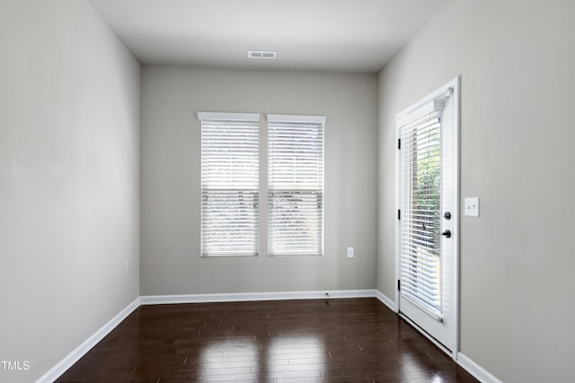 spare room featuring dark wood-style flooring and baseboards