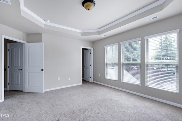 unfurnished bedroom with a raised ceiling, carpet, crown molding, and baseboards