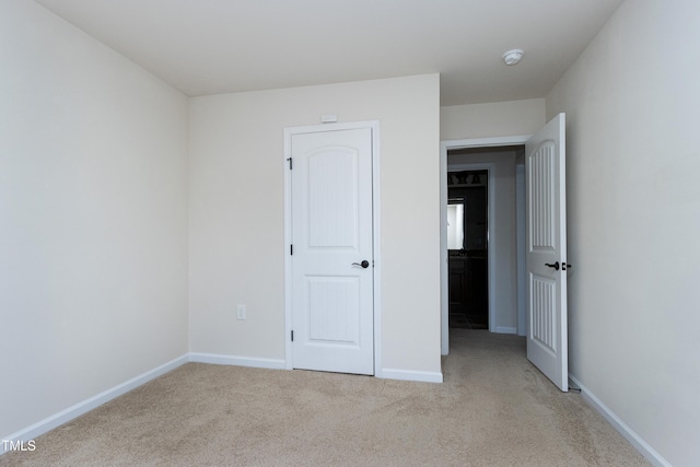 unfurnished bedroom featuring light carpet and baseboards