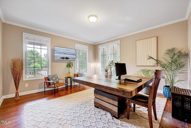 home office featuring wood finished floors, ornamental molding, plenty of natural light, and baseboards