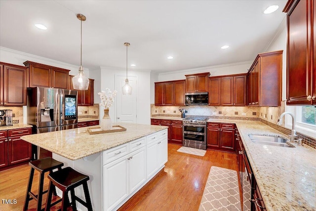 kitchen with appliances with stainless steel finishes, a sink, a center island, backsplash, and ornamental molding