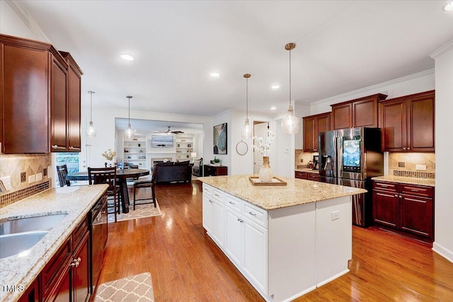 kitchen featuring appliances with stainless steel finishes, open floor plan, wood finished floors, a kitchen island, and crown molding
