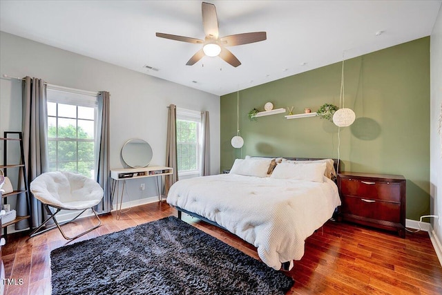bedroom featuring multiple windows, wood finished floors, baseboards, and ceiling fan