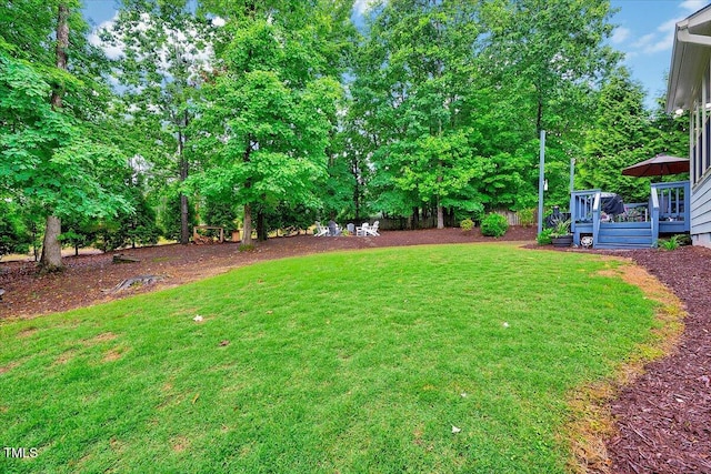 view of green lawn with a wooden deck